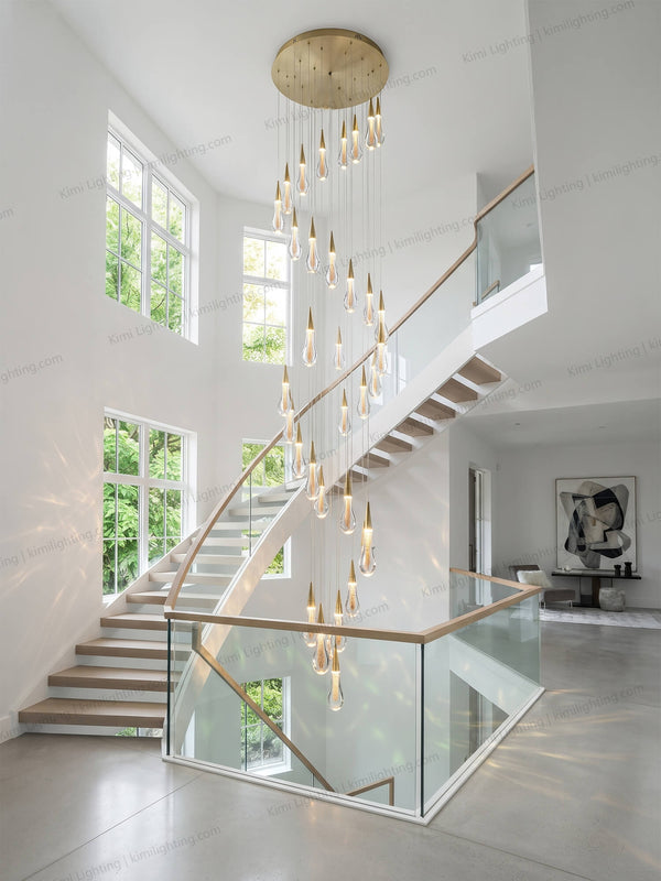 Modern raindrop glass pendant lighting brightens a high ceiling staircase.