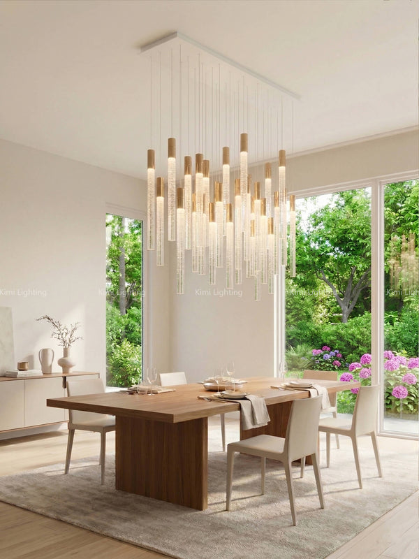 Linear cylindrical crystal chandelier over a dining table with trendy avant-garde urban style.